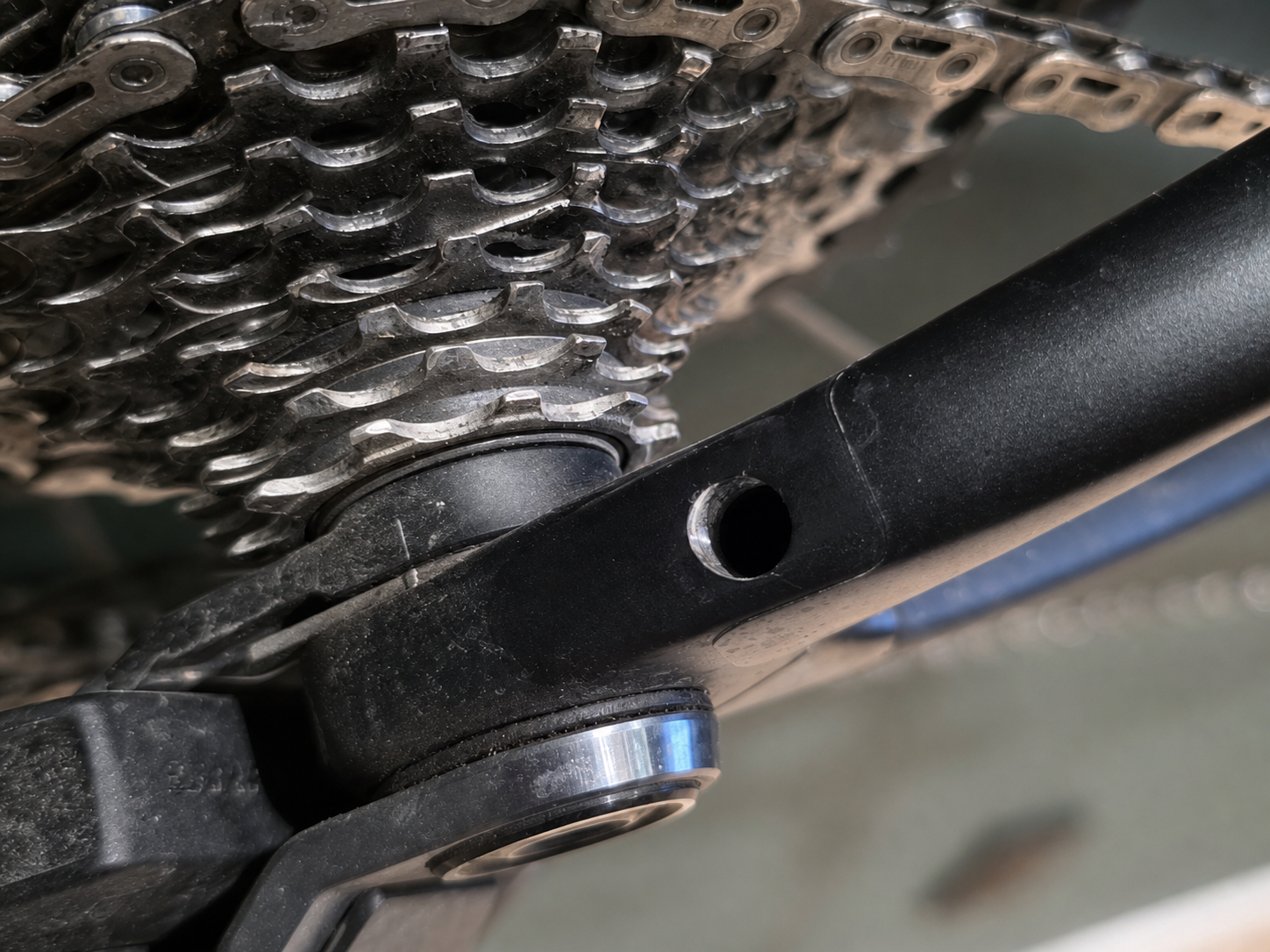 Close-up of a circular opening in a black bicycle frame beside the drivetrain before installation